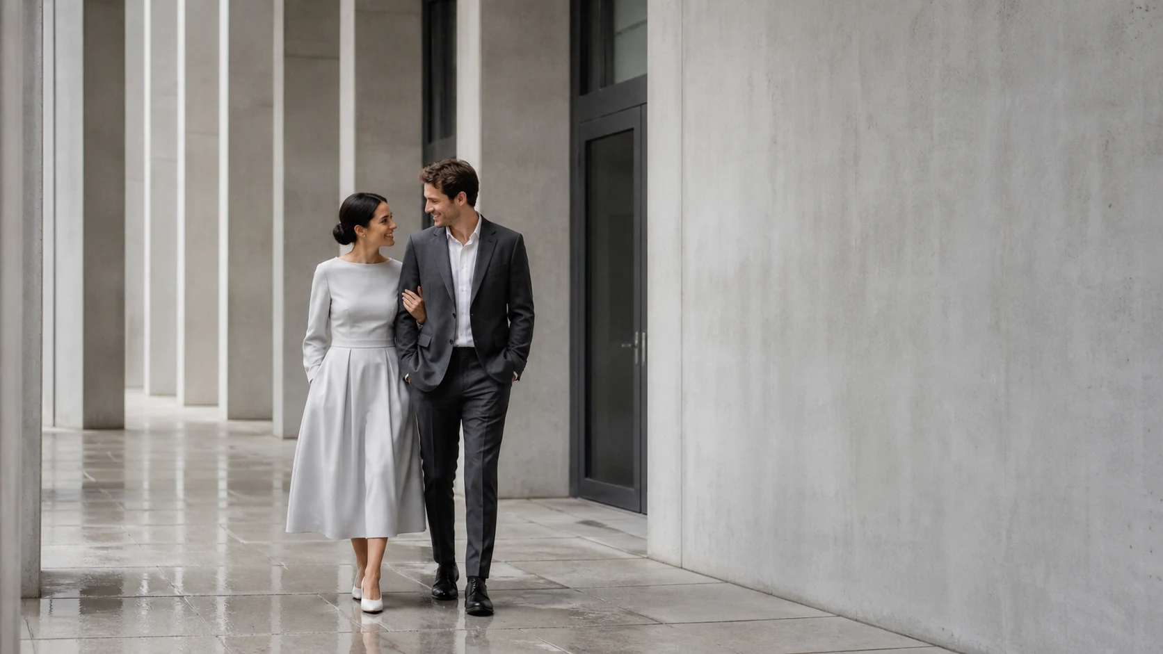 Pareja joven caminando junta por un espacio arquitectónico de tonos grises